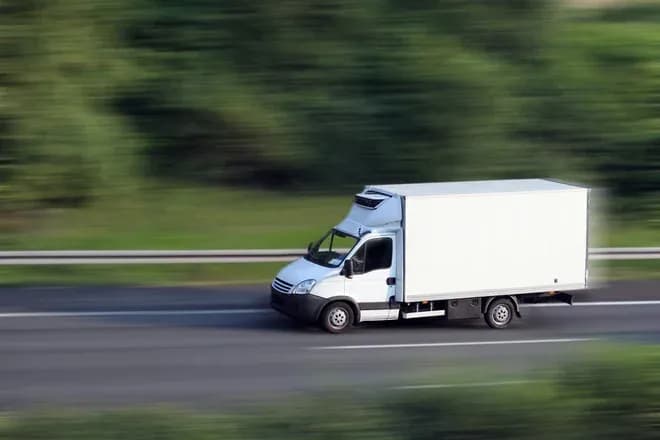camion frigorifique en mouvement sur une route bordée d'arbres flous