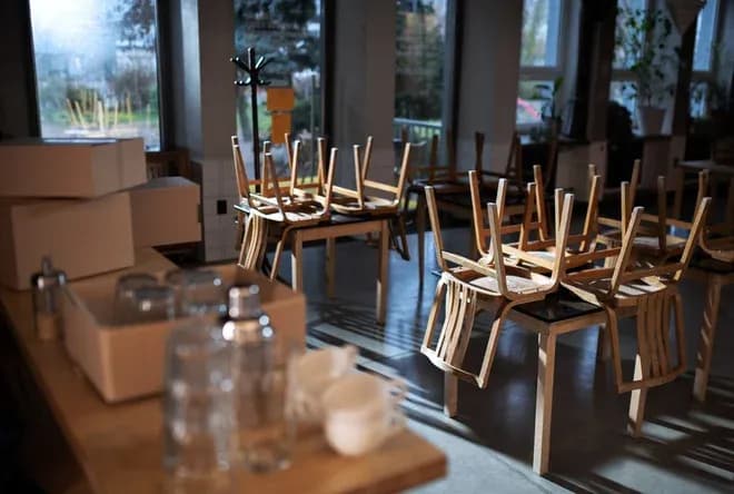 salle de restaurant avec des chaises retournées et des cartons sur une table en bois