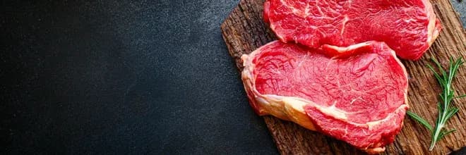 morceaux de viande rouge sur une planche en bois avec une branche de romarin à côté