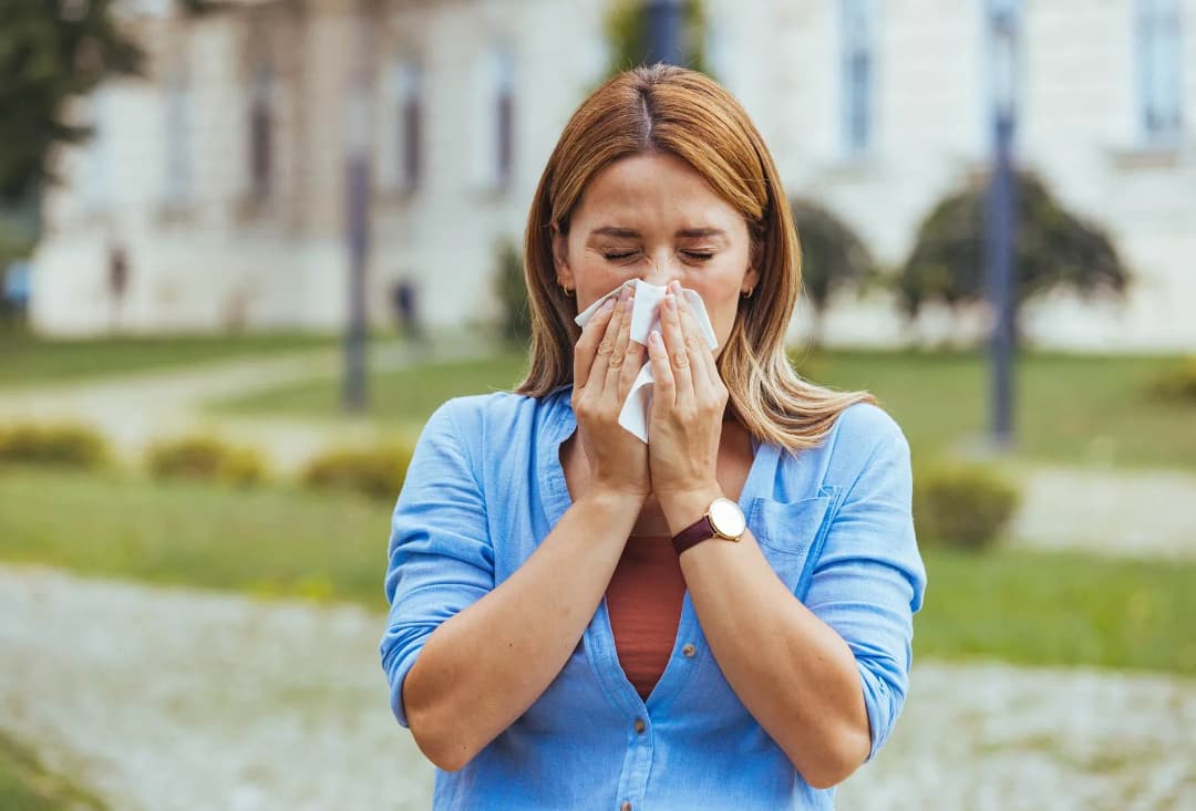 femme se mouchant dans un mouchoir dans un parc avec un air de gêne