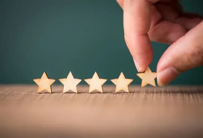 main dans un geste de classement de cinq étoiles en bois sur une surface en carton