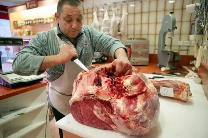 Boucher en train de découper un morceau de viande dans une charcuterie moderne