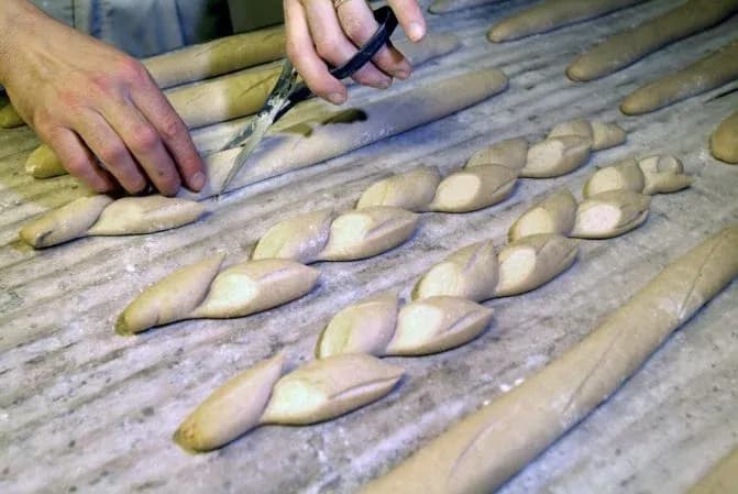 main d'un boulanger façonnant des pâtes à pain sur une surface de travail en bois
