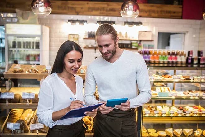 deux vendeurs en boulangerie consultent une tablette pendant que l'une note