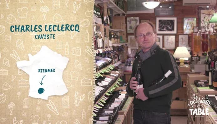 caviste présentant une bouteille de vin dans un magasin rempli de bouteilles et d'accessoires