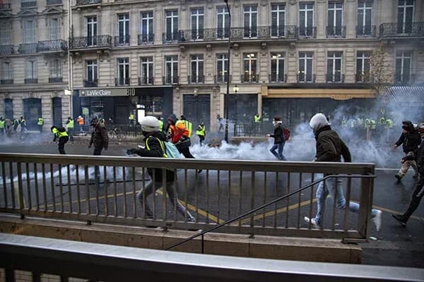 manifestation avec des personnes courant dans un nuage de gaz lacrymogène en milieu urbain