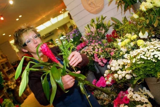 fleuriste arrangeant des fleurs dans un magasin rempli de bouquets colorés