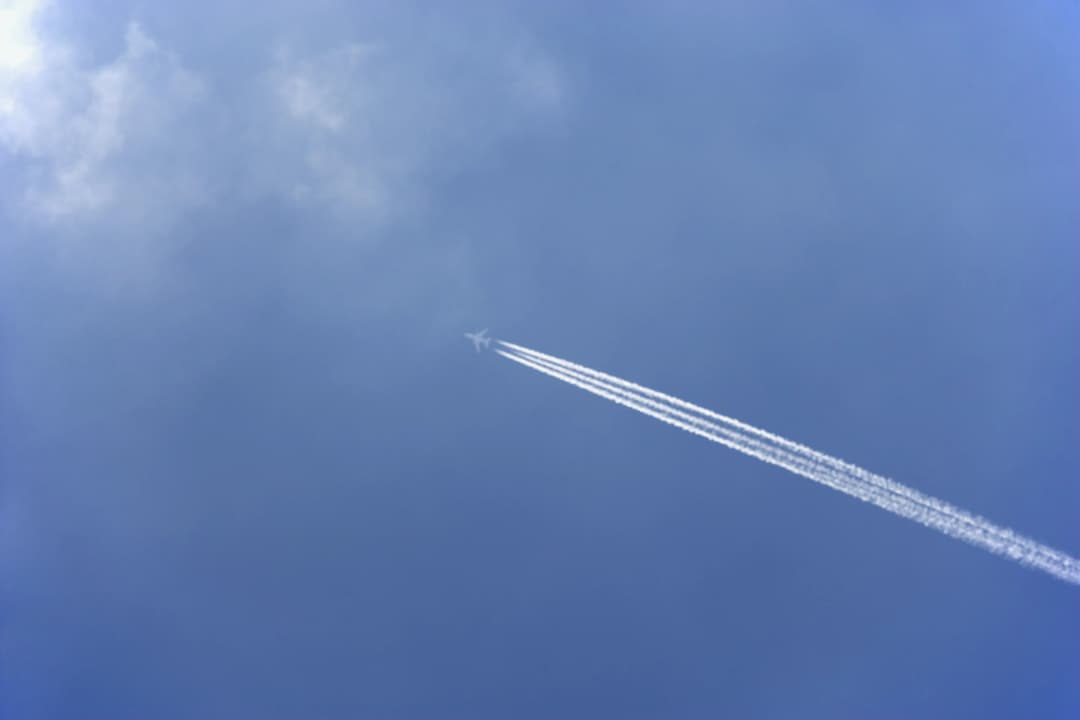 avion dans le ciel laissant une traînée de condensation derrière lui