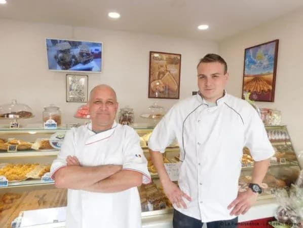 Deux boulangers souriants devant des pâtisseries dans une boulangerie artisanale