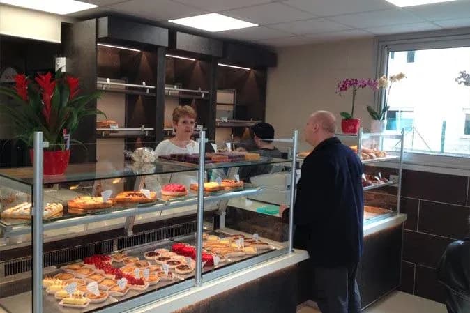 boulangerie avec une vitrine de pâtisseries et un client en discussion avec la vendeuse