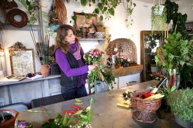 fleuriste préparant un bouquet dans un atelier décoré de plantes et d'objets naturels