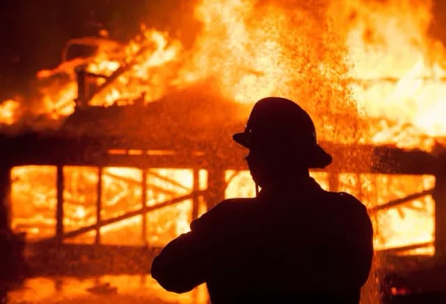 siluette d'un pompier devant un incendie dévastateur dans un bâtiment en feu