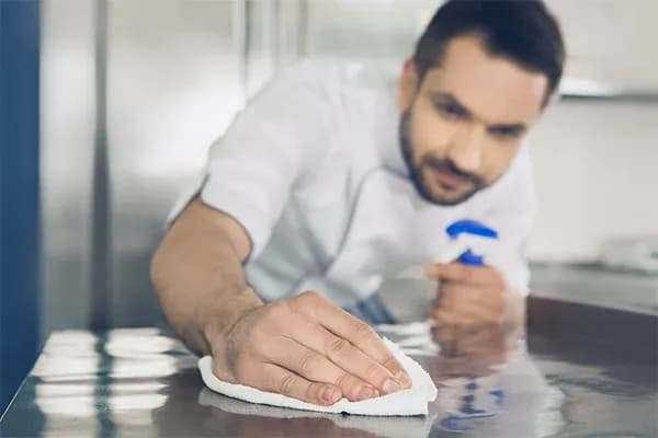 un professionnel de la cuisine nettoie un plan de travail avec un chiffon humide