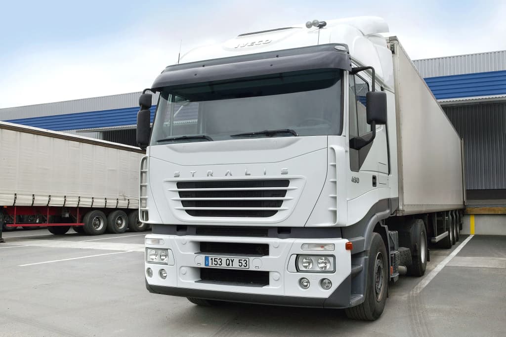 camion de transport blanc stationné dans un entrepôt avec remorque à l'arrière