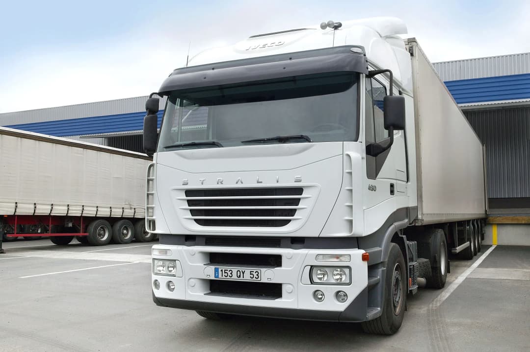 camion de transport blanc stationné dans un entrepôt avec remorque à l'arrière