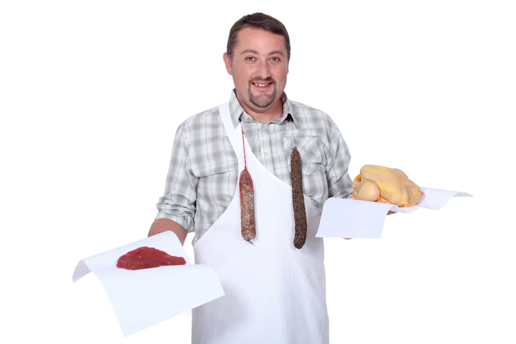 Homme souriant en tablier tenant des morceaux de viande et de charcuterie sur des plateaux blancs