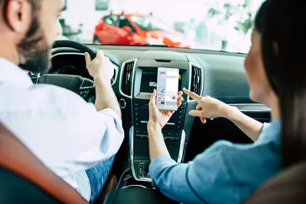 personnes dans une voiture montrant un document sur un smartphone avec un véhicule en arrière-plan
