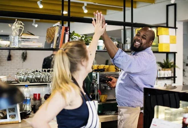 collaboration joyeuse entre deux personnes dans un café avec un barista et une cliente