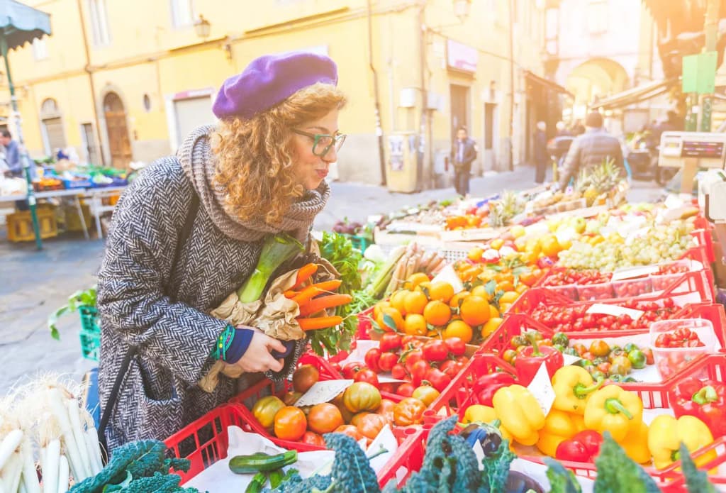 femme regardant des légumes et fruits frais sur un marché en plein air ensoleillé