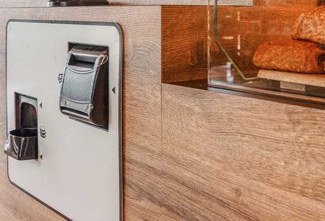 distributeur de produits alimentaires intégré dans un comptoir en bois avec des viennoiseries visibles