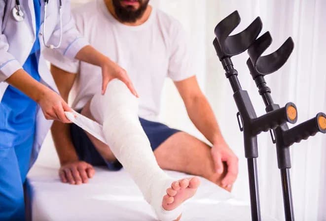 soin d'un patient avec une jambe plâtrée et des béquilles à proximité