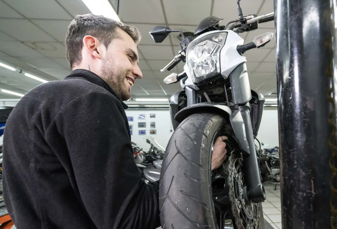 mécanicien inspectant la roue d'une moto dans un atelier de réparation