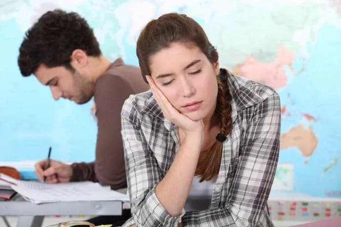 élève fatiguée avec la tête posée sur la main en arrière-plan d'une carte du monde