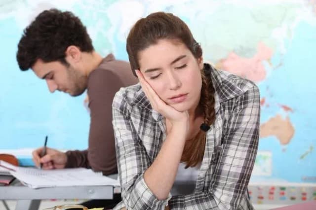 élève fatiguée avec la tête posée sur la main en arrière-plan d'une carte du monde