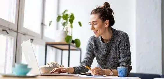 femme souriante travaillant sur un ordinateur portable dans un environnement lumineux et moderne