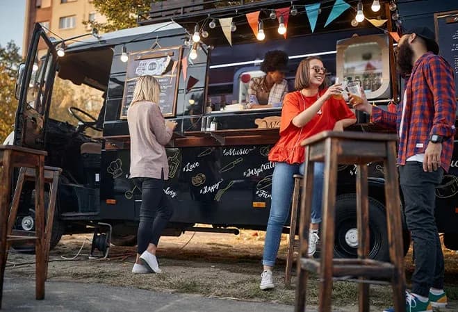 groupe de personnes profitant d'un food truck avec des boissons et une ambiance festive