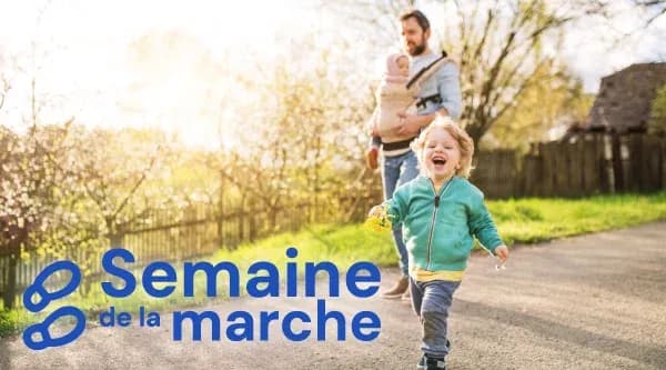 enfant souriant courant sur un chemin avec un adulte portant un bébé en arrière-plan