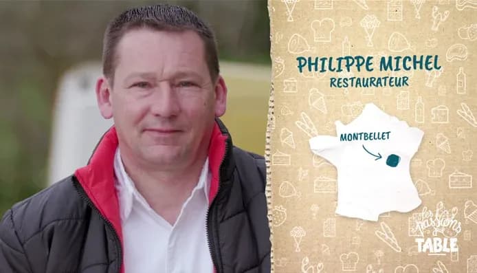 restaurateur avec un blouson noir et rouge devant une carte de France indiquant Montbellet