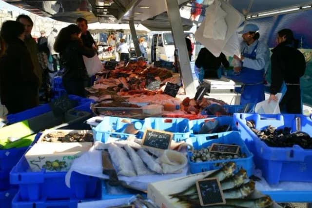 marché de poisson avec étals de fruits de mer et clients en discussion autour des produits