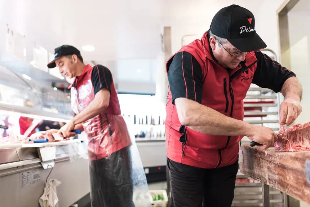 bouchers travaillant dans une charcuterie avec des outils de découpe et des produits frais