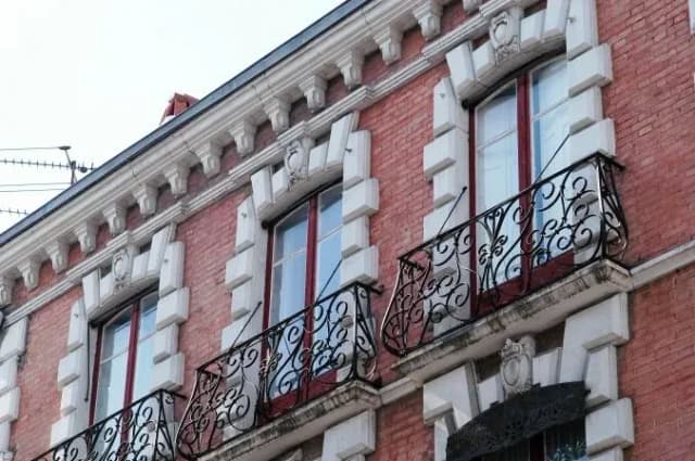 façade d'un immeuble ancien avec balcons en fer forgé et fenêtres à encadrement blanc