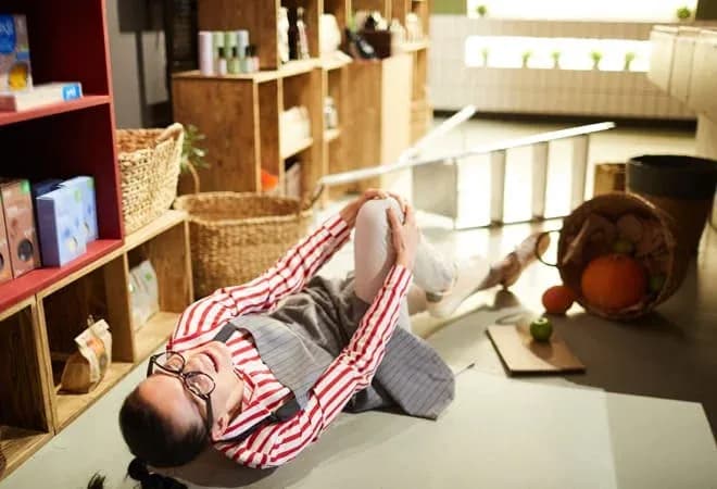 femme blessée au sol dans un magasin de restauration avec des étagères en bois autour d'elle