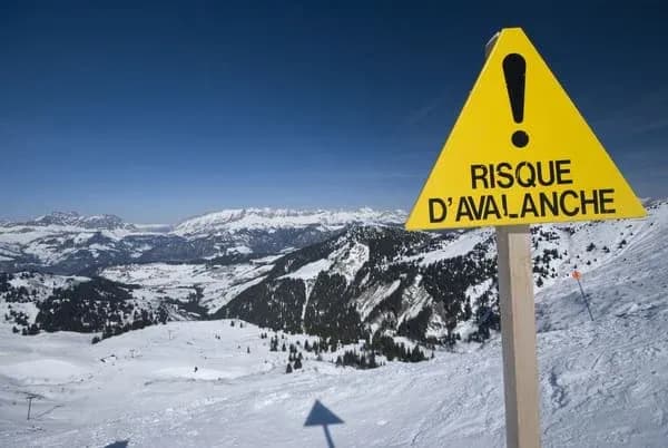 panneau d'avertissement sur le risque d'avalanche en montagne avec paysage enneigé en arrière-plan