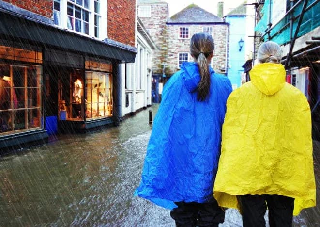 deux personnes portant des imperméables bleu et jaune marchent dans une rue inondée