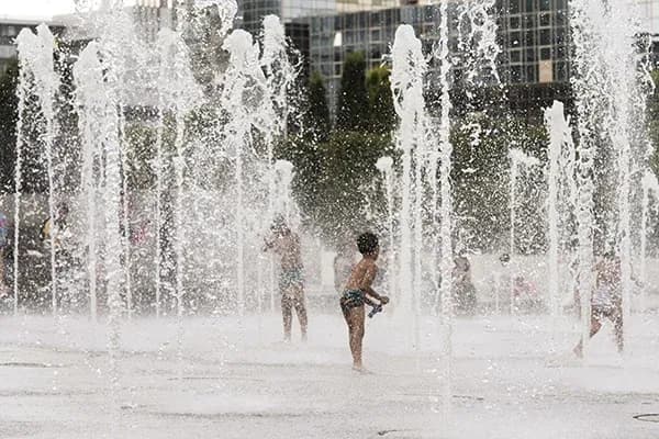 enfants jouant dans un jeu d'eau en été avec des jets d'eau autour d'eux