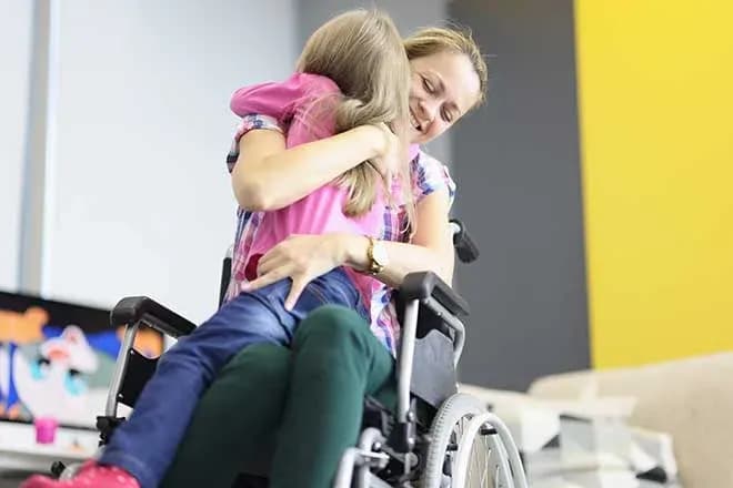 femme en fauteuil roulant étreignant une enfant dans un cadre chaleureux et accueillant
