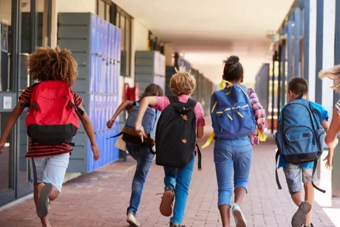 groupe d'enfants courant dans un couloir d'école avec des sacs à dos colorés