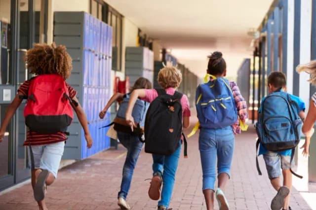 groupe d'enfants courant dans un couloir d'école avec des sacs à dos colorés