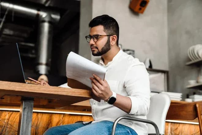homme assis à une table avec des documents dans les mains dans un café moderne