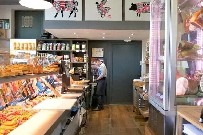 boucherie avec un employé préparant des produits frais et des étagères bien approvisionnées