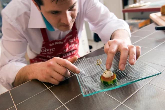 traiteur plaçant avec précision une bouchée sur une assiette en verre