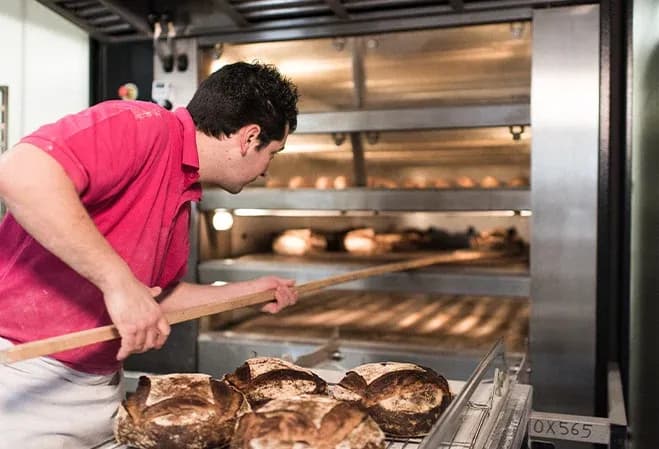 boulanger enfournant des miches au four