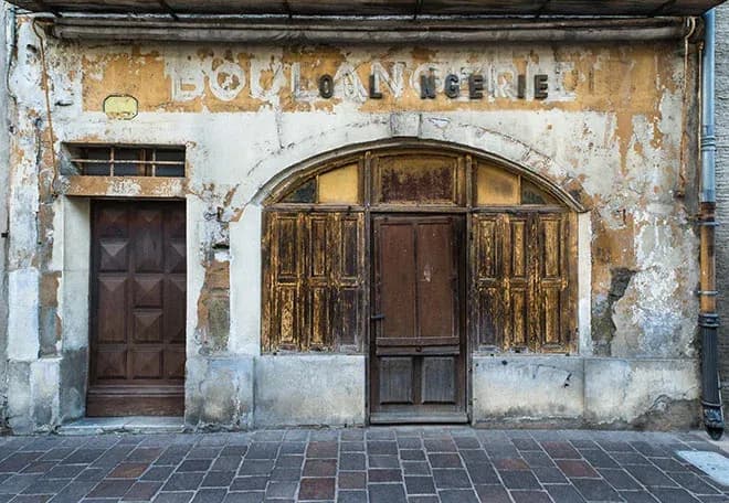 façade de boulangerie abandonnée avec peinture écaillée et volets en bois usés