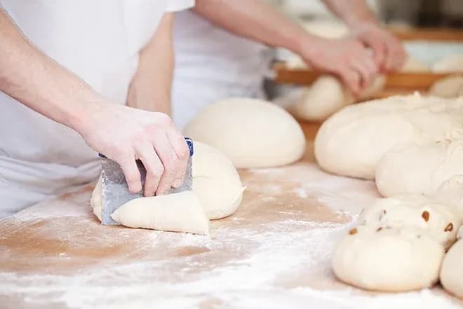 pâtissiers travaillant la pâte à pain sur un plan de travail fariné