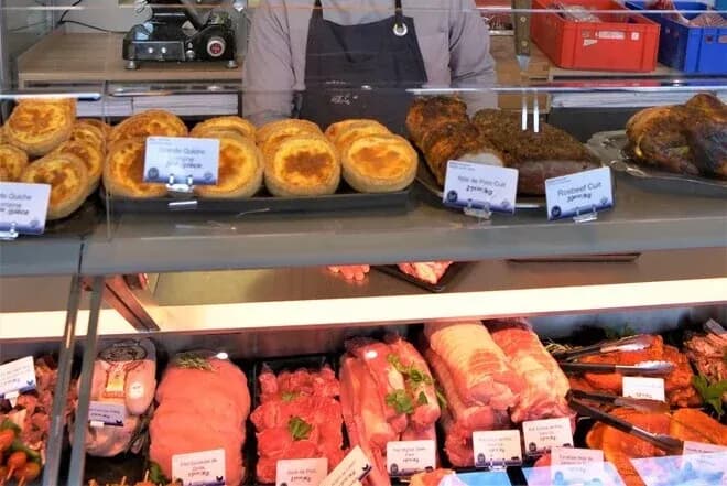 vitrine de boucherie avec viandes découpées et quiches exposées