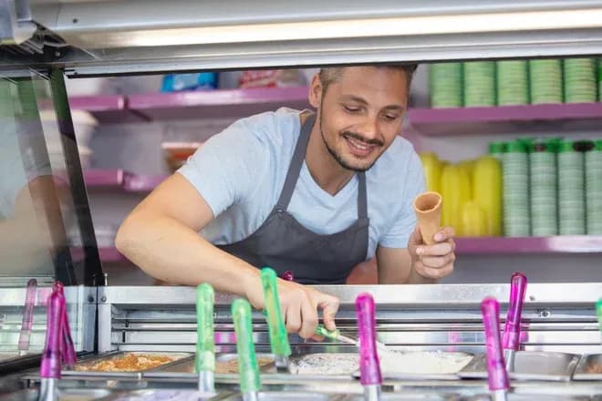 Homme souriant servant une glace dans un camion à glace avec des cornets à la main